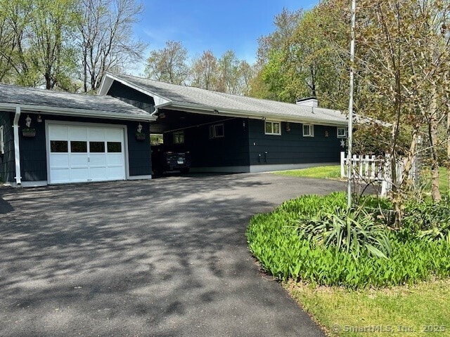 view of front of property featuring aphalt driveway, a garage, a chimney, and an attached carport