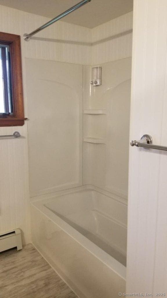 bathroom with a baseboard radiator, shower / bathing tub combination, and wood finished floors