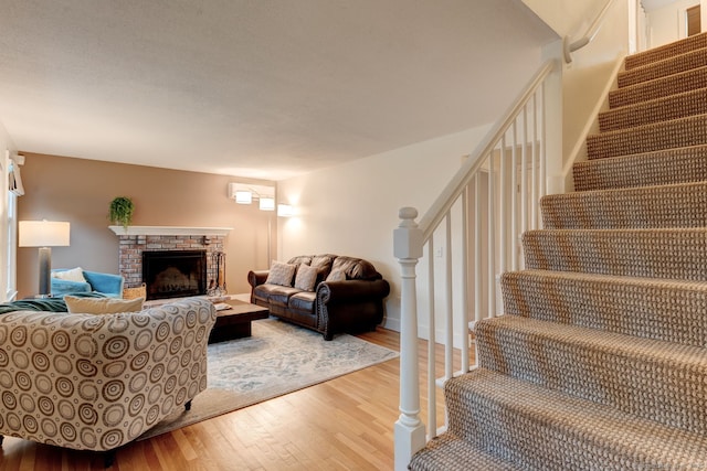 living room with wood finished floors, stairway, and a fireplace