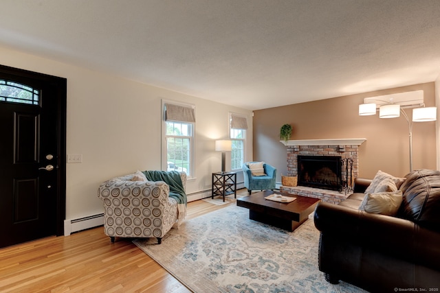 living room with light wood-style flooring, a fireplace, and baseboard heating