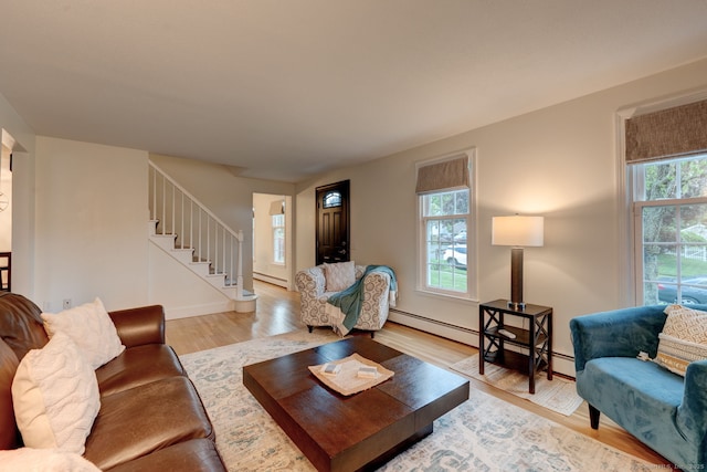 living room featuring stairs, a baseboard radiator, light wood-style floors, and baseboards