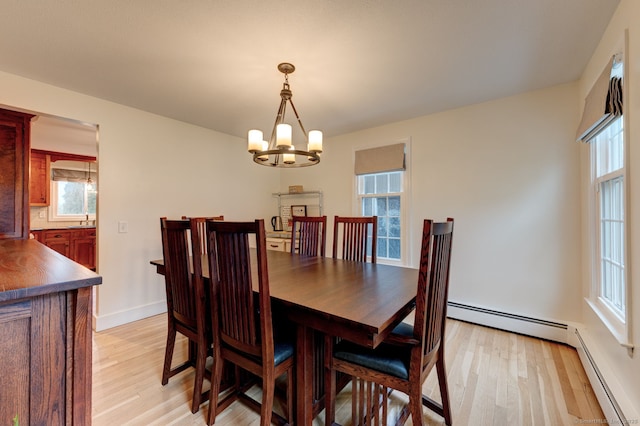 dining area featuring light wood-style floors, a chandelier, baseboard heating, and baseboards