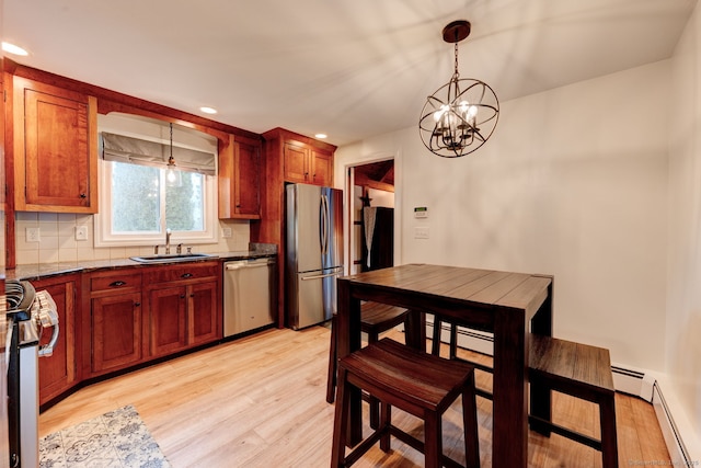kitchen featuring appliances with stainless steel finishes, a sink, a chandelier, light wood-type flooring, and a baseboard heating unit
