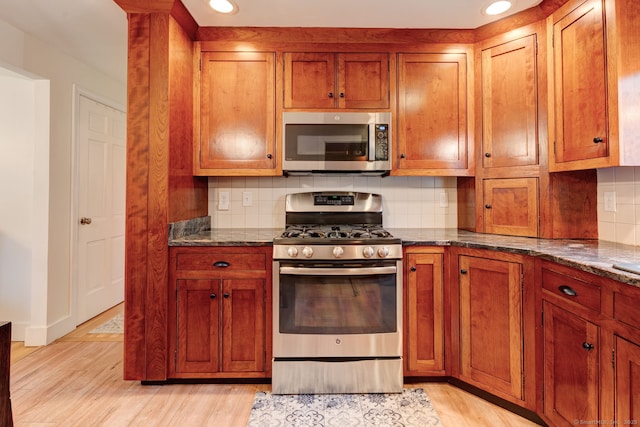 kitchen featuring appliances with stainless steel finishes, light wood-style flooring, brown cabinets, decorative backsplash, and recessed lighting