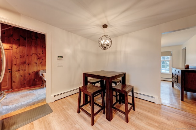 dining space featuring a baseboard radiator, light wood-style flooring, and a chandelier
