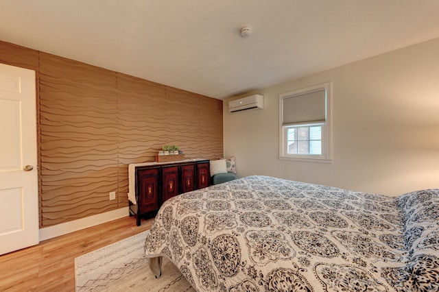 bedroom featuring an AC wall unit and light wood-style flooring