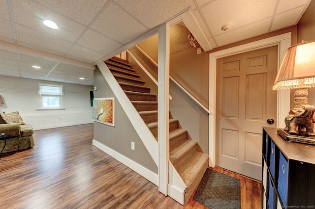 stairs featuring a drop ceiling, wood finished floors, baseboards, and recessed lighting
