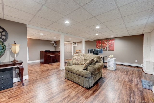 living area featuring wood finished floors, baseboards, a baseboard heating unit, a paneled ceiling, and recessed lighting