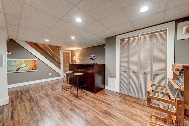 indoor dry bar with wood finished floors, a paneled ceiling, recessed lighting, and baseboards