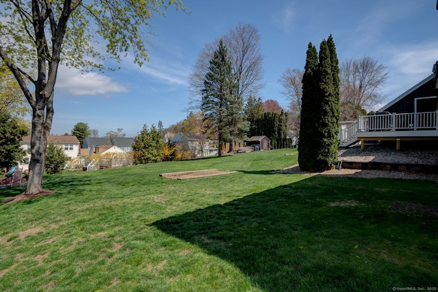 view of green lawn with a wooden deck