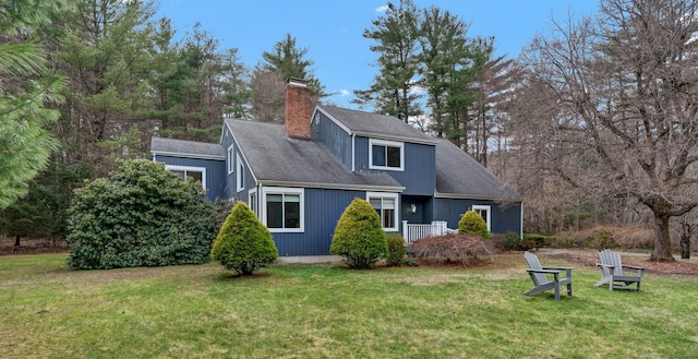 view of front of property with a chimney, a front lawn, and a shingled roof