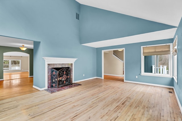 unfurnished living room featuring high vaulted ceiling, wood finished floors, a fireplace, and baseboards