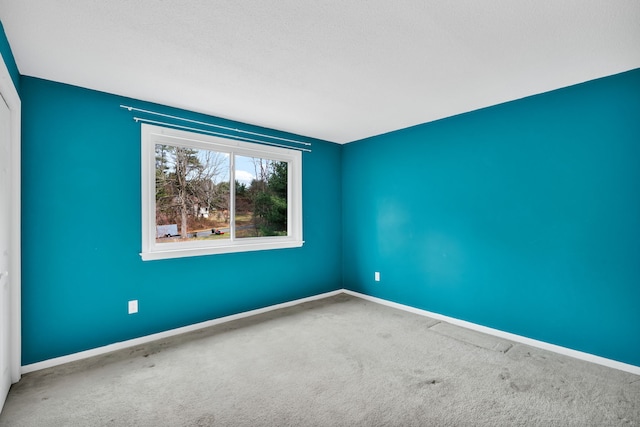 carpeted empty room featuring baseboards