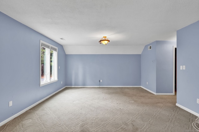 carpeted spare room featuring baseboards, lofted ceiling, and a textured ceiling