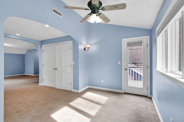 additional living space featuring arched walkways, lofted ceiling, carpet flooring, baseboards, and ceiling fan