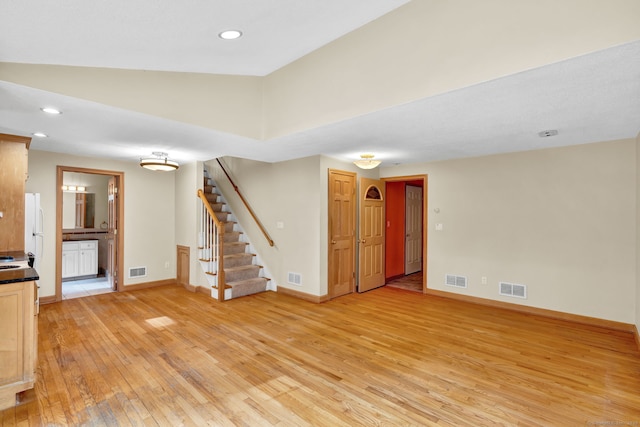 unfurnished living room with light wood-style flooring, stairway, baseboards, and recessed lighting