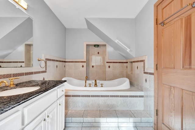 full bathroom with a bath, vanity, tile walls, and wainscoting