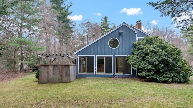 back of house with a chimney, a lawn, and a pergola