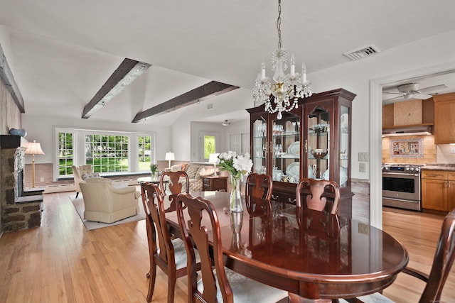 dining space with a baseboard radiator, light wood-style flooring, visible vents, a fireplace, and beam ceiling
