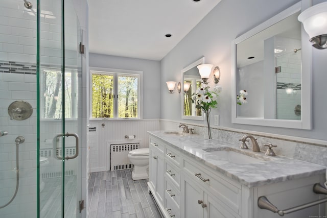 bathroom with a sink, wainscoting, toilet, and radiator