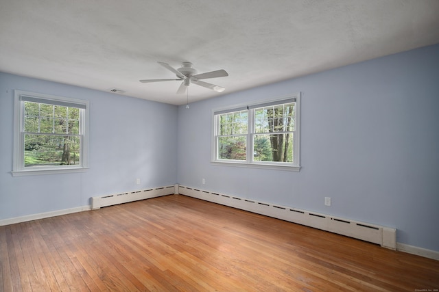 unfurnished room featuring a ceiling fan, hardwood / wood-style floors, visible vents, baseboards, and baseboard heating