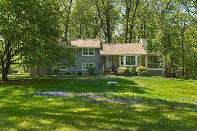tri-level home with a front lawn and a chimney