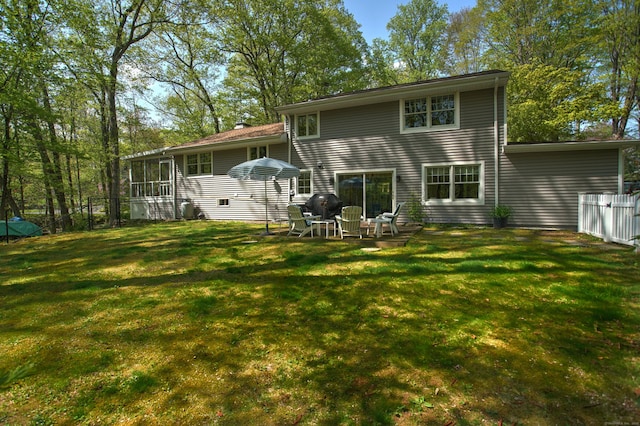 rear view of property featuring a yard, a sunroom, and fence