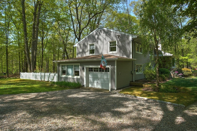 exterior space featuring gravel driveway, a front yard, an attached garage, and fence