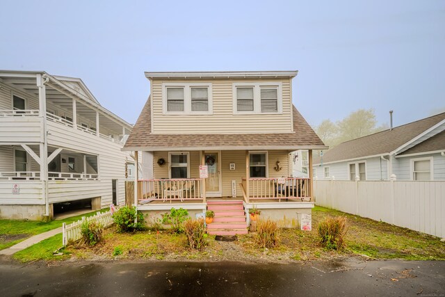 bungalow-style home featuring a shingled roof, a porch, and fence