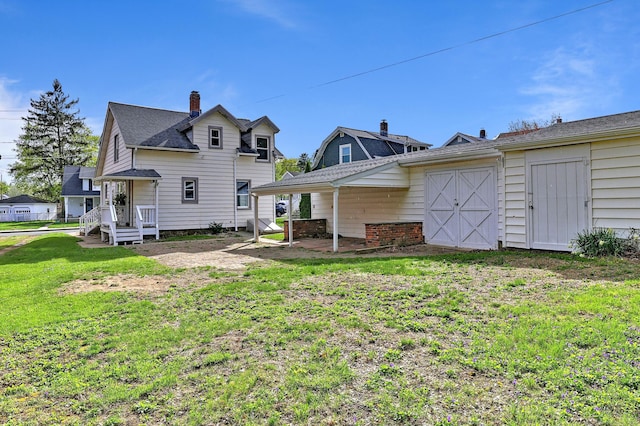 rear view of property featuring a lawn and a chimney