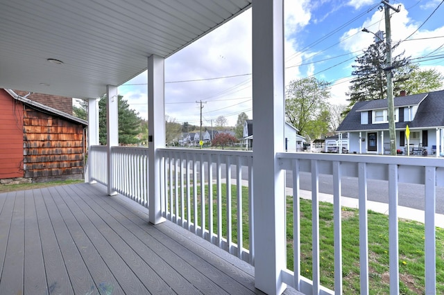 wooden terrace with a porch, a yard, and a residential view