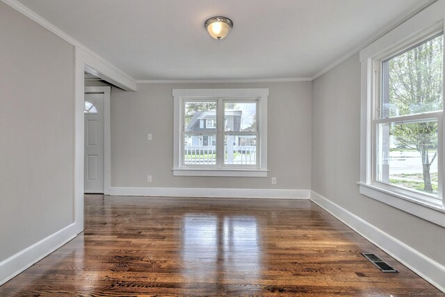 unfurnished room with a wealth of natural light, ornamental molding, visible vents, and dark wood-style flooring