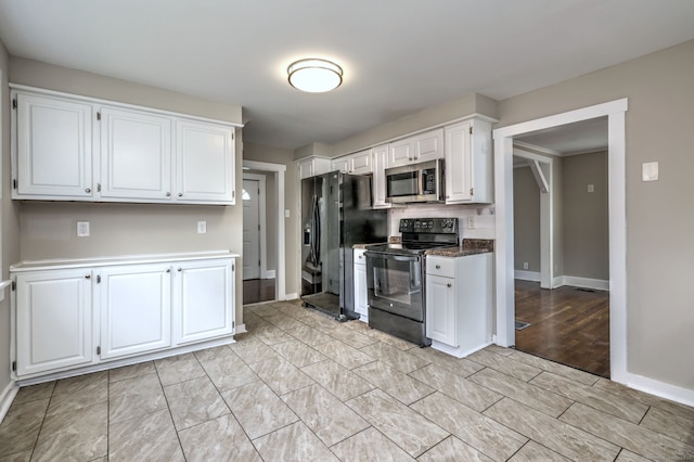 kitchen featuring white cabinetry, decorative backsplash, baseboards, and black appliances