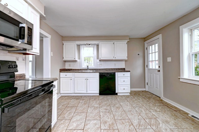 kitchen featuring baseboards, a sink, white cabinets, black appliances, and tasteful backsplash