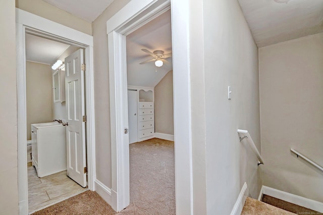 hallway featuring baseboards, an upstairs landing, and carpet floors