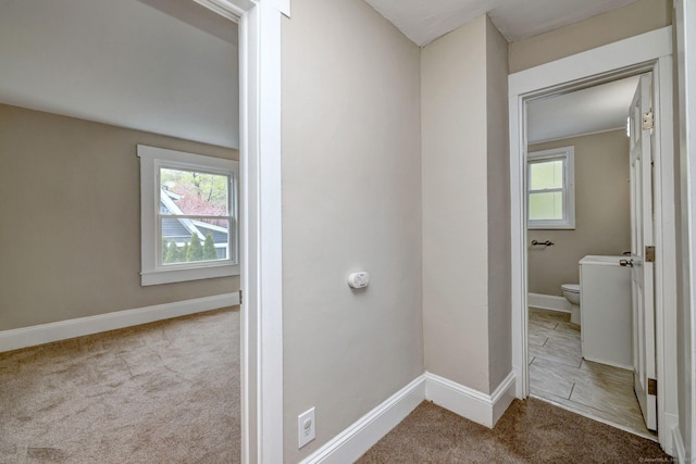 hall featuring carpet flooring and baseboards