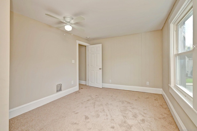 carpeted empty room featuring visible vents, baseboards, and ceiling fan