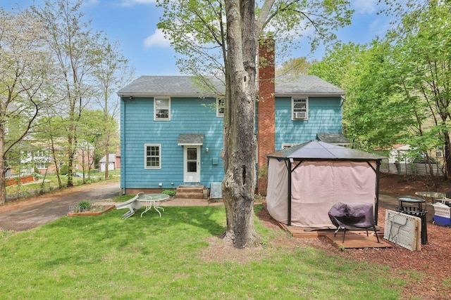 rear view of house with a yard, a gazebo, entry steps, and a shingled roof