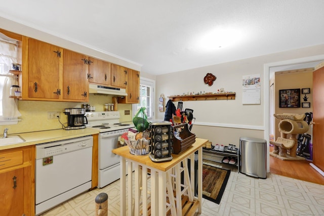 kitchen with light floors, white appliances, a sink, and under cabinet range hood