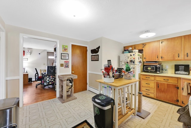 kitchen featuring a baseboard heating unit, light floors, black microwave, and light countertops