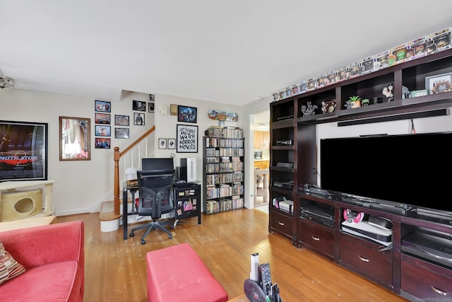 living area with stairway, light wood-style flooring, and baseboards