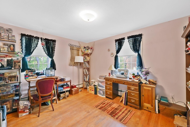 office featuring a baseboard radiator, light wood finished floors, and plenty of natural light