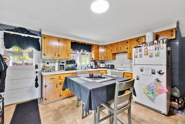 kitchen with brown cabinets, white appliances, light countertops, and a sink