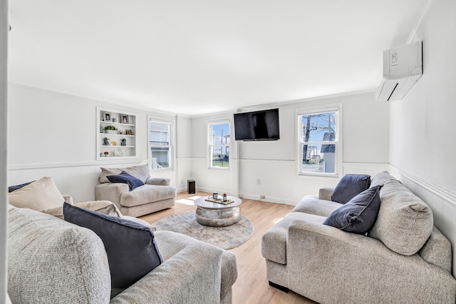 living room featuring a wall mounted AC, light wood finished floors, a wainscoted wall, healthy amount of natural light, and ornamental molding