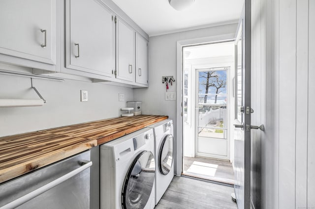 laundry area featuring independent washer and dryer, cabinet space, and light wood-style flooring