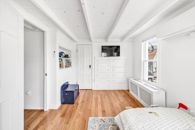 bedroom with a wall mounted air conditioner, wood finished floors, radiator heating unit, and beamed ceiling