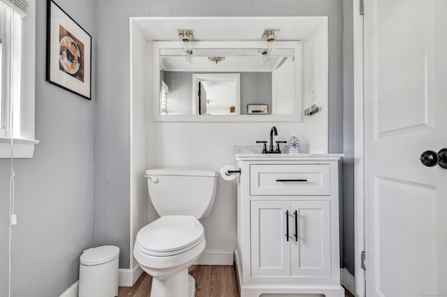 half bath featuring wood finished floors, toilet, and vanity