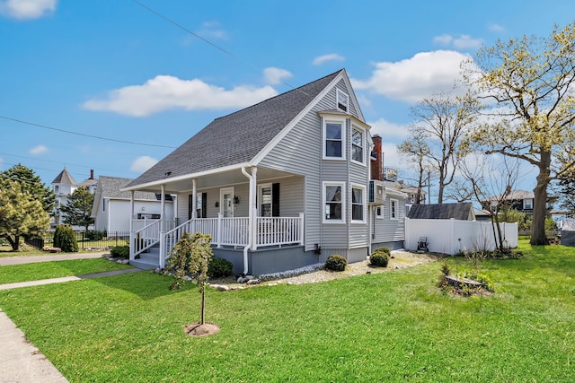 view of front of house with a porch, a front lawn, and a shingled roof