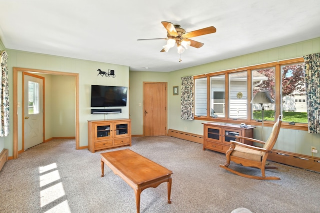 living area featuring baseboard heating, a ceiling fan, carpet floors, and baseboards