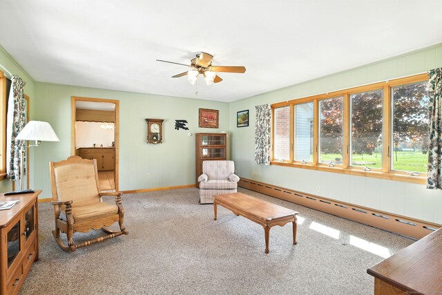 living area featuring a ceiling fan, a baseboard radiator, carpet, and baseboards